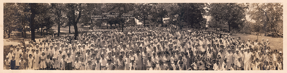 Donnelly Garment Company Annual Picnic at Winnwood Beach, July 19, 1930. Many employees in attendance are wearing Nelly Don-branded clothing pieces like hats and dresses.