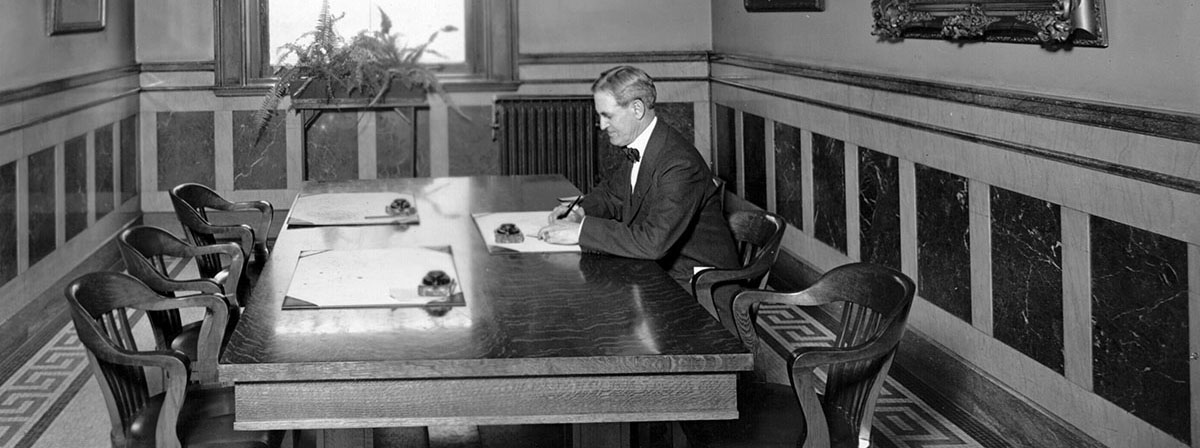 Man writing a letter at a large wooden table