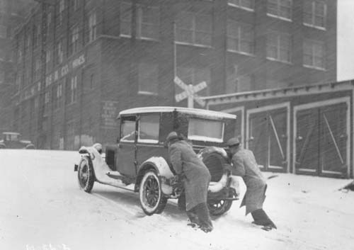 two men pushing a car through the snow