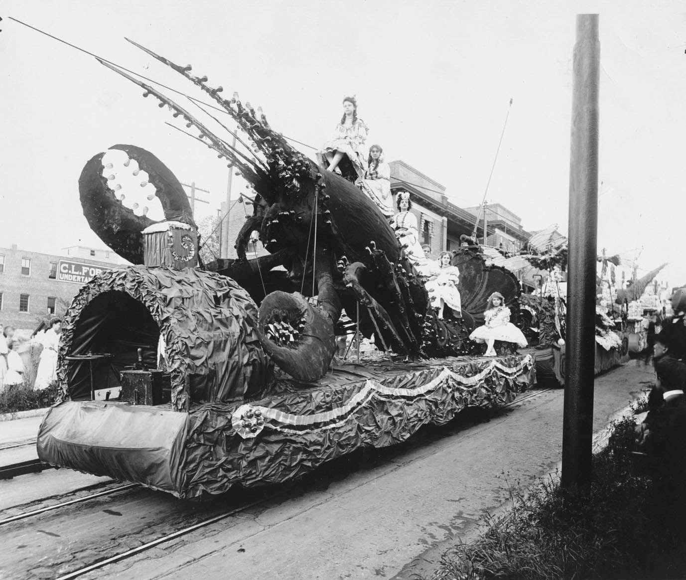 Women in costume atop float bearing oversized lobster