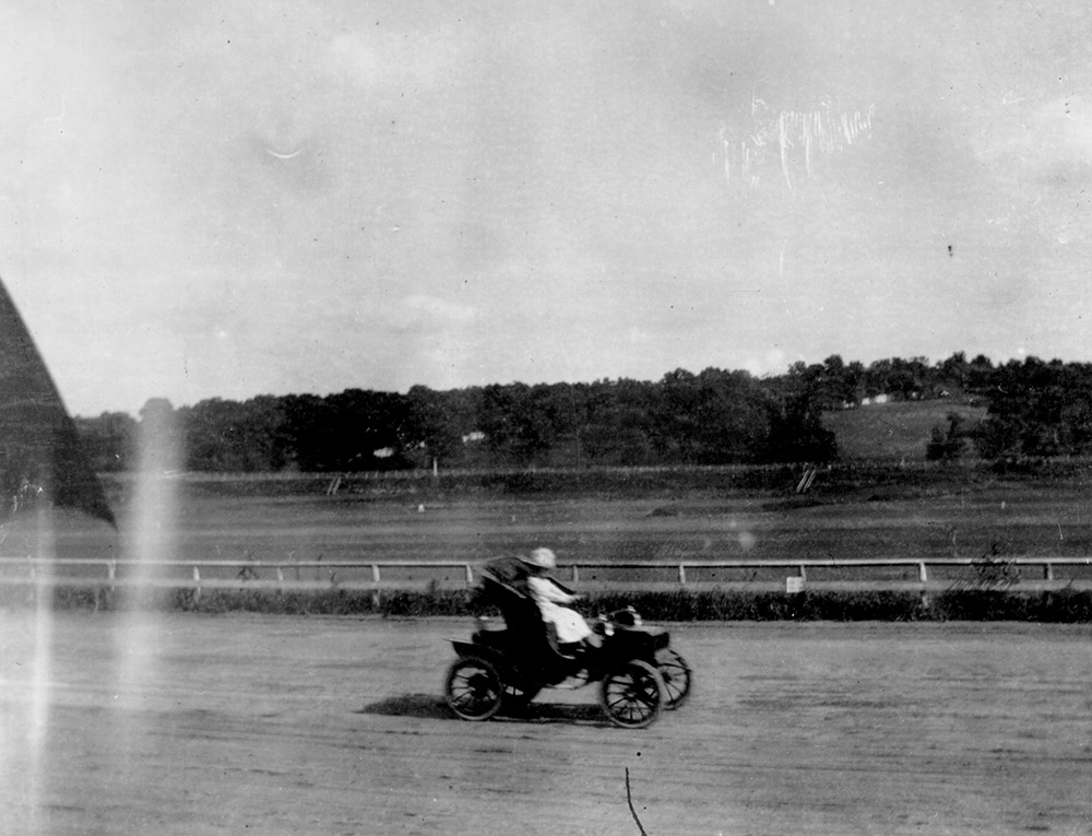 Car driving on Old Elm Ridge Race Track. Driver is a woman.