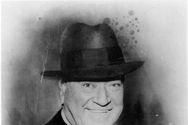 Portrait of Tom Pendergast who is smiling and wearing a hat