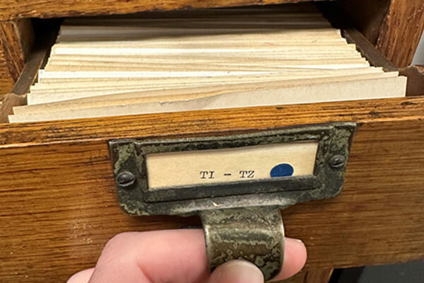 close view of a hand opening a card catalog