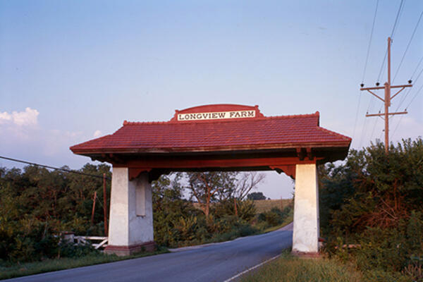 Color photograph of a red and white gateway with a sign for Longview Farm