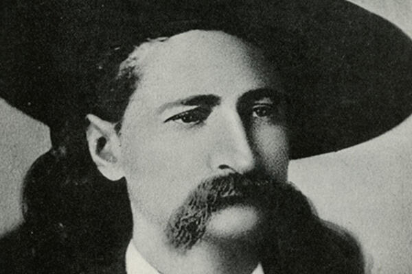 Portrait of a mustachioed man wearing a cowboy hat