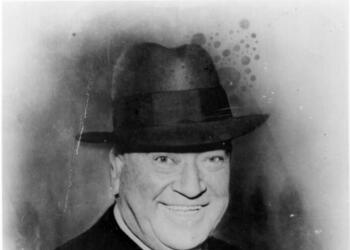 Portrait of Tom Pendergast who is smiling and wearing a hat