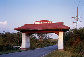 Color photograph of a red and white gateway with a sign for Longview Farm