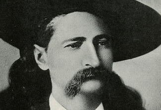 Portrait of a mustachioed man wearing a cowboy hat